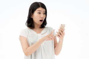 スマホを見て驚く女性